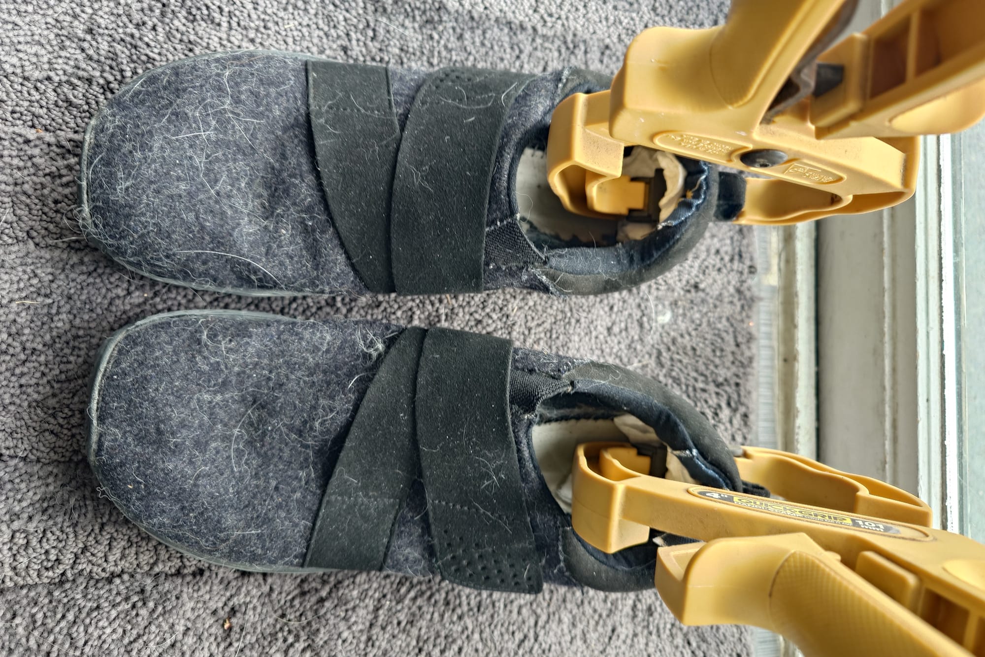 Shoes on grey carpet, with yellow clamps inside the heels holding fabric in place.